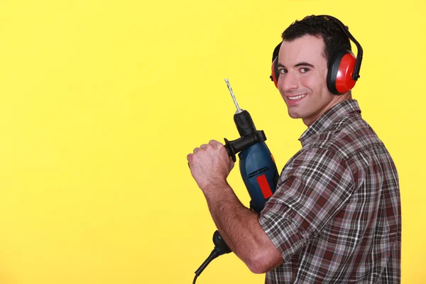 Homem vestindo muff ouvido protetor e segurando broca de energia — Fotografia de Stock