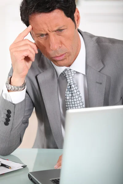 Homme d'affaires avec une expression perplexe regardant un écran d'ordinateur — Photo