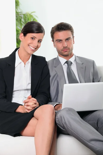 Businessman and businesswoman in front of a laptop computer — Stok fotoğraf