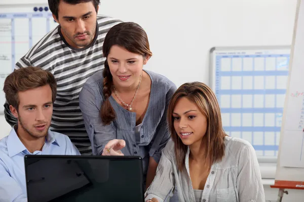Jovens reunidos em torno de um laptop — Fotografia de Stock