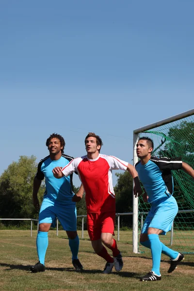 Tres futbolistas esperando el balón delante del gol —  Fotos de Stock