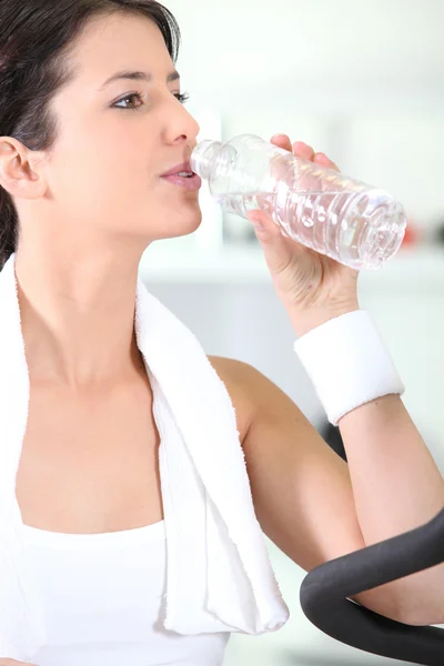 Donna che beve da una bottiglia d'acqua in palestra — Foto Stock