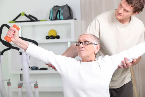 Trener pomaga starszy kobieta robi fitness — Zdjęcie stockowe