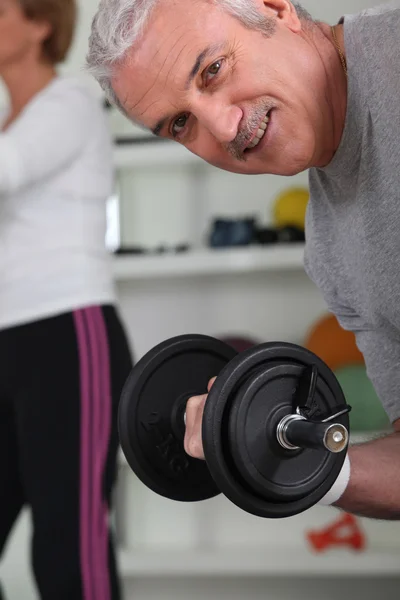 Smiling mature man lifting barbell — Stock Photo, Image