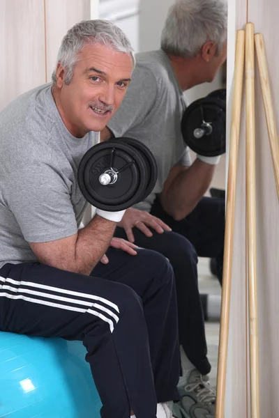 Grauhaariger Mann, der Gewichte stemmt — Stockfoto