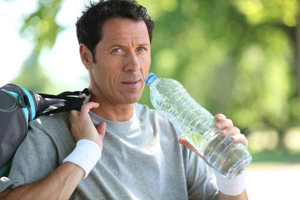 Man in sports clothes drinking water — Stock Photo, Image