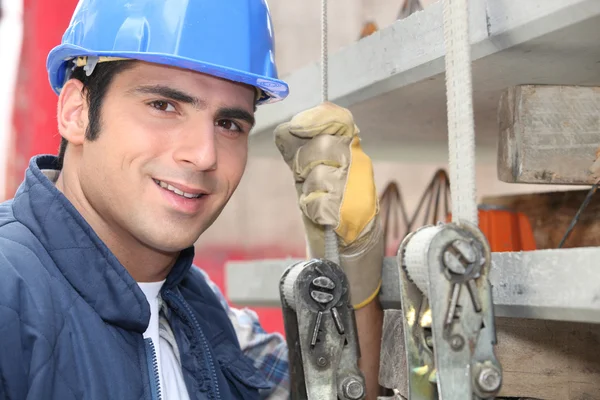 Tradesman standing next to a hoist — Stock Photo, Image