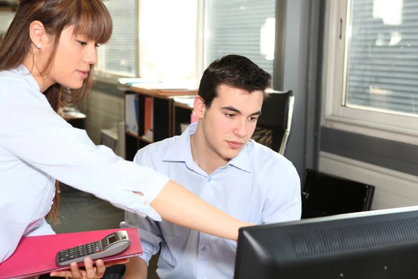 Woman explaining something on a computer to her colleague — Stock Photo, Image