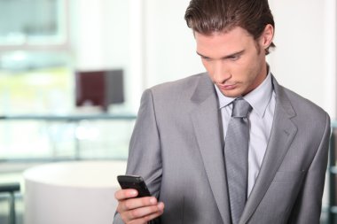 Male executive checking messages on cellphone clipart
