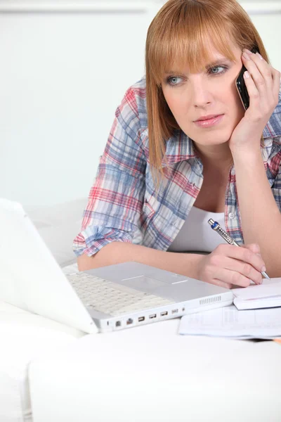 Frau am Telefon bei der Arbeit am Laptop — Stockfoto