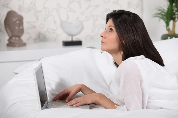 Kvinna med sin laptop i sängen — Stockfoto