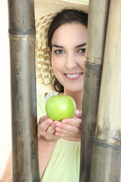 Жінка тримає яблуко стояла біля бамбука — стокове фото
