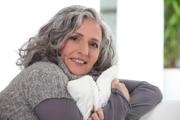 Señora de pelo gris sosteniendo cojín — Foto de Stock