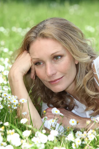 Woman lying in the daisies — Stock Photo, Image