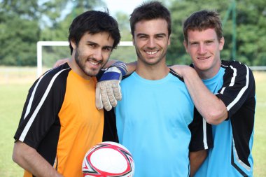 Three football players in casual clothes posing for the photo clipart