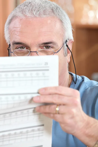 Mann mit Brille liest ein bedrucktes Blatt — Stockfoto