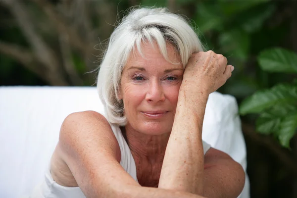 Grey-haired woman sat in garden — Stock Photo, Image