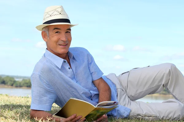 Старший чоловік читає на траві — стокове фото