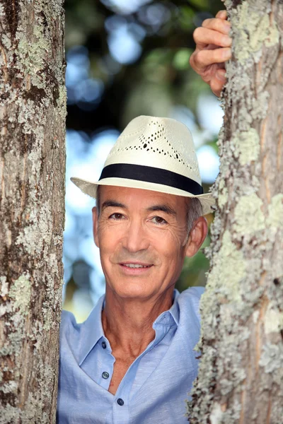 Nosit klobouk muž stál mezi dvěma stromy — Stock fotografie