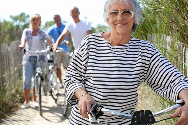 Oudere vrouw en vrienden op een fietstocht — Stockfoto