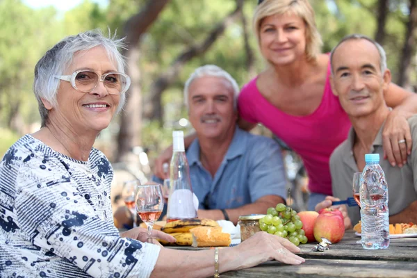 Mujer mayor haciendo un picnic con amigos — Foto de Stock