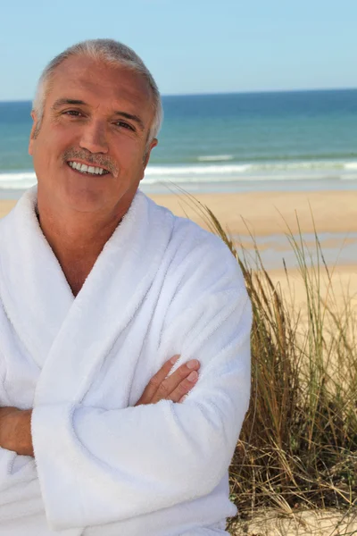 Homem de cabelos grisalhos em roupão de banho estava na praia — Fotografia de Stock