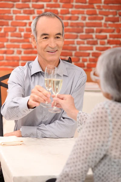 Pareja mayor bebiendo champán en un restaurante — Foto de Stock