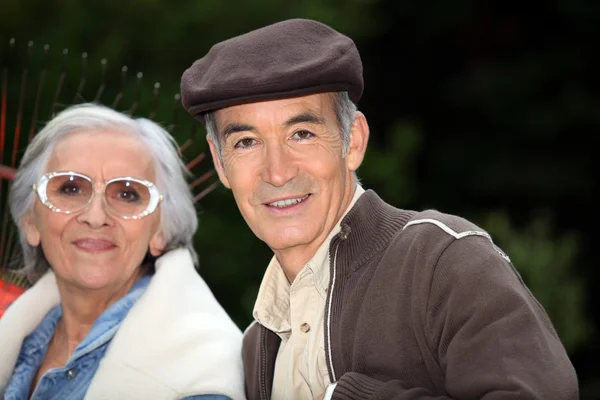 Пожилая пара с садовыми граблями — стоковое фото
