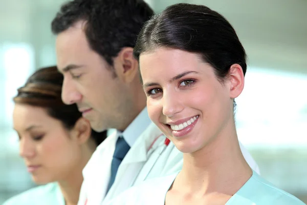Sorridente infermiera ospedaliera in piedi con i colleghi — Foto Stock