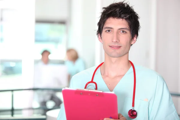 Молодой врач в больничной форме с планшетом — стоковое фото