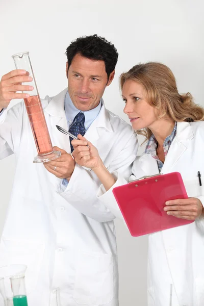 Técnicos de laboratorio examinando líquido rosa — Foto de Stock