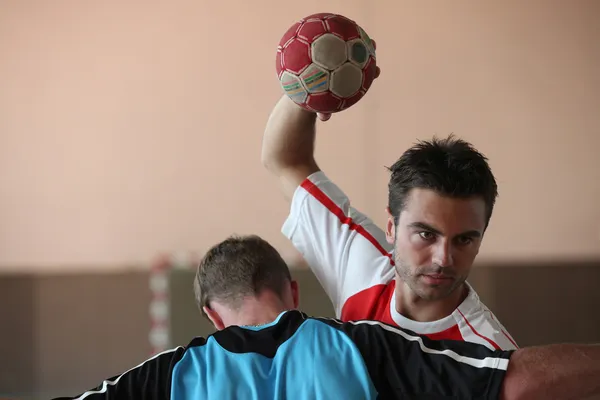 Um homem jogando handebol e tentando marcar, apesar de um goleiro em fron — Fotografia de Stock