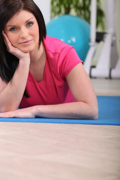 Молодая женщина делает упражнения на полу в спортзале — стоковое фото