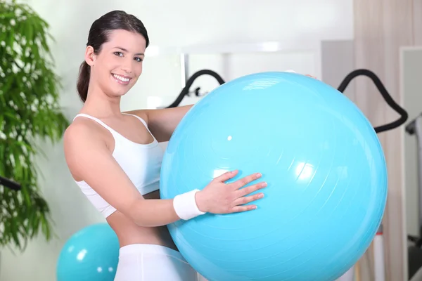Mulher sorridente com uma bola de exercício em um ginásio — Fotografia de Stock