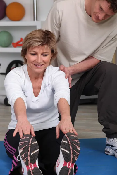 Mogen kvinna gör övning med hjälp av sjukgymnast — Stockfoto