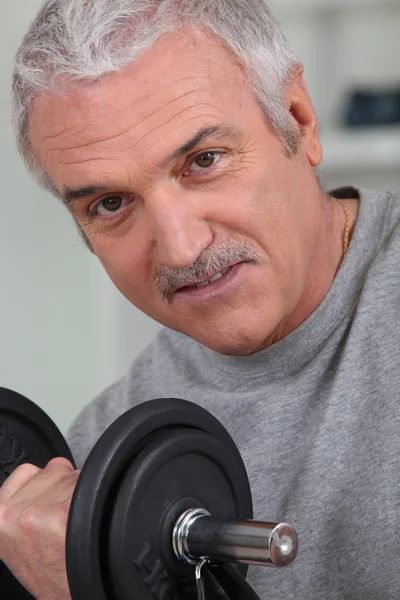 Senior man doing exercises with a dumbbell — Stock Photo, Image