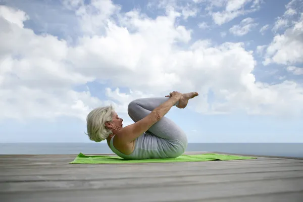 Senior woman making exercises on the beach — Stock Photo, Image