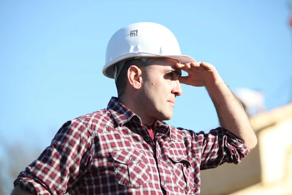Tradesman que protege seus olhos da luz solar — Fotografia de Stock