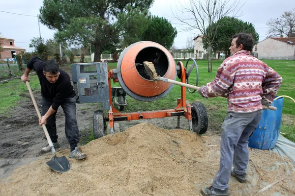 Двое мужчин смешивают цемент — стоковое фото