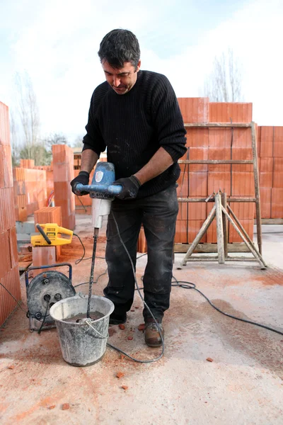 Trabalhador usando um batedor de remo de cimento — Fotografia de Stock