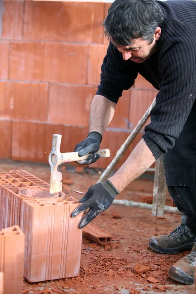 Construtor martelando um tijolo — Fotografia de Stock
