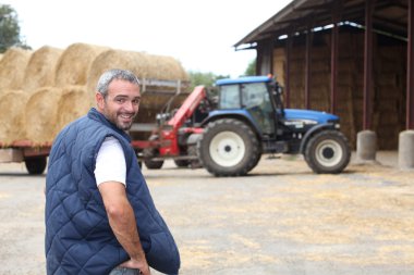 Famer stood by hay barn clipart
