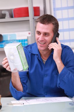 Man checking product details by phone in a plumber's merchants clipart