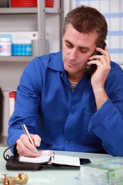 Man in overalls with a phone and ringbound organizer clipart