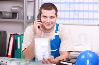 Plumber in an office checking a part clipart