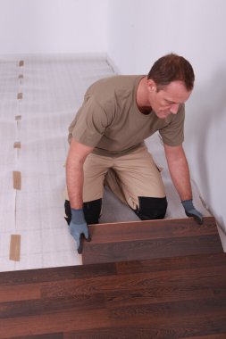Handy-man laying wooden flooring clipart