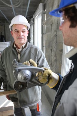 Construction workers talking about a tool clipart