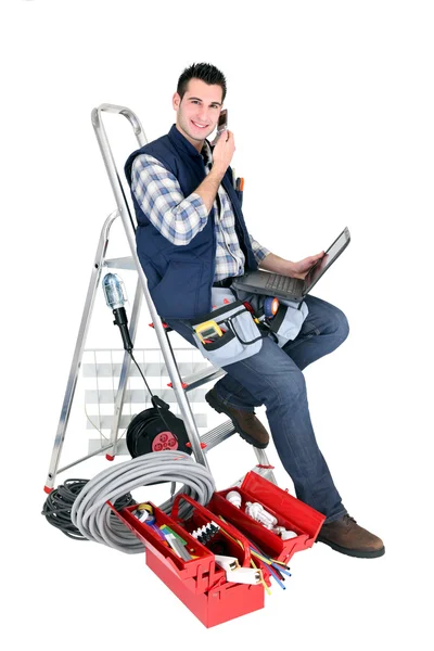 Eletricista com telefone e laptop — Fotografia de Stock