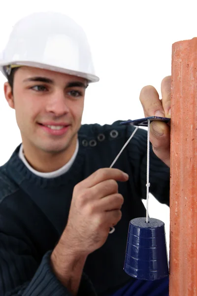 Handsome bricklayer fixing bell on brick wall — Stock Photo, Image