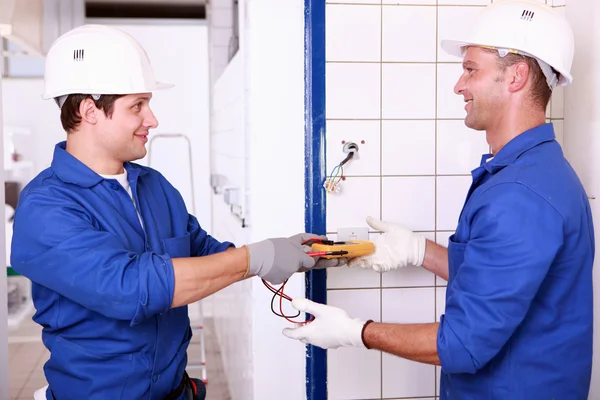 Dois engenheiros elétricos masculinos verificando a fonte de alimentação — Fotografia de Stock